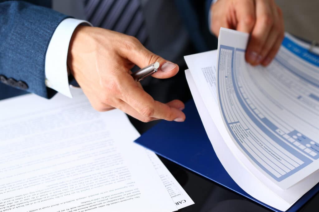 a lawyer holding a pen over a blue folder with car accident claim documents