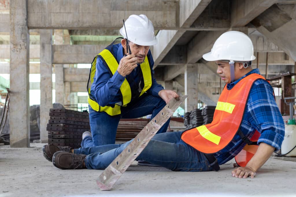 Factory worker in a hard hat holding his neck after an on-the-job injury