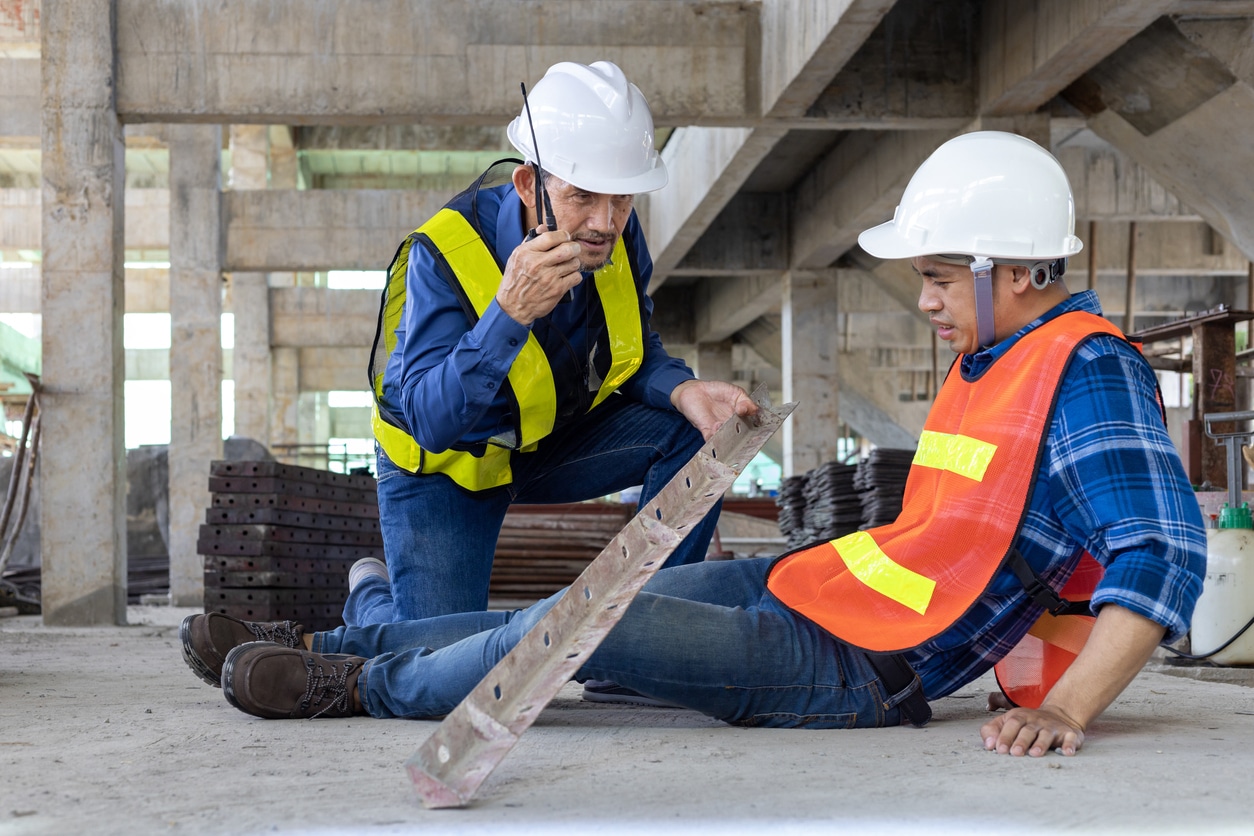 Factory worker in a hard hat holding his neck after an on-the-job injury