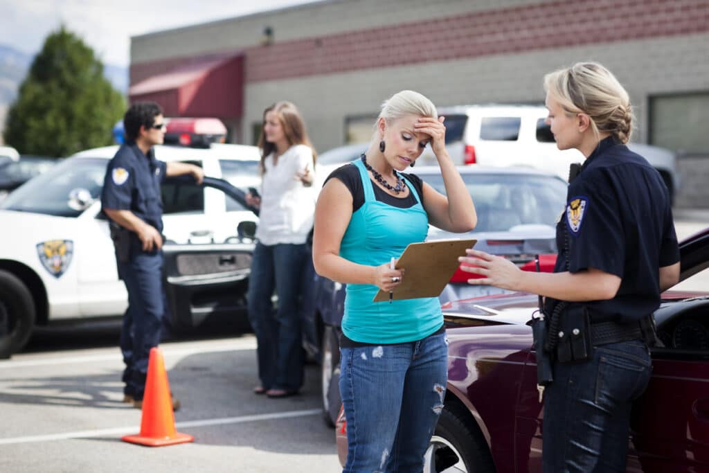 Police officer taking a driver statement on a clipboard at a traffic accident scene