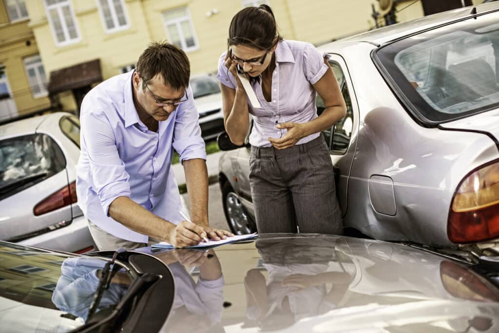 Two drivers exchanging insurance details and filling out an accident report after a collision